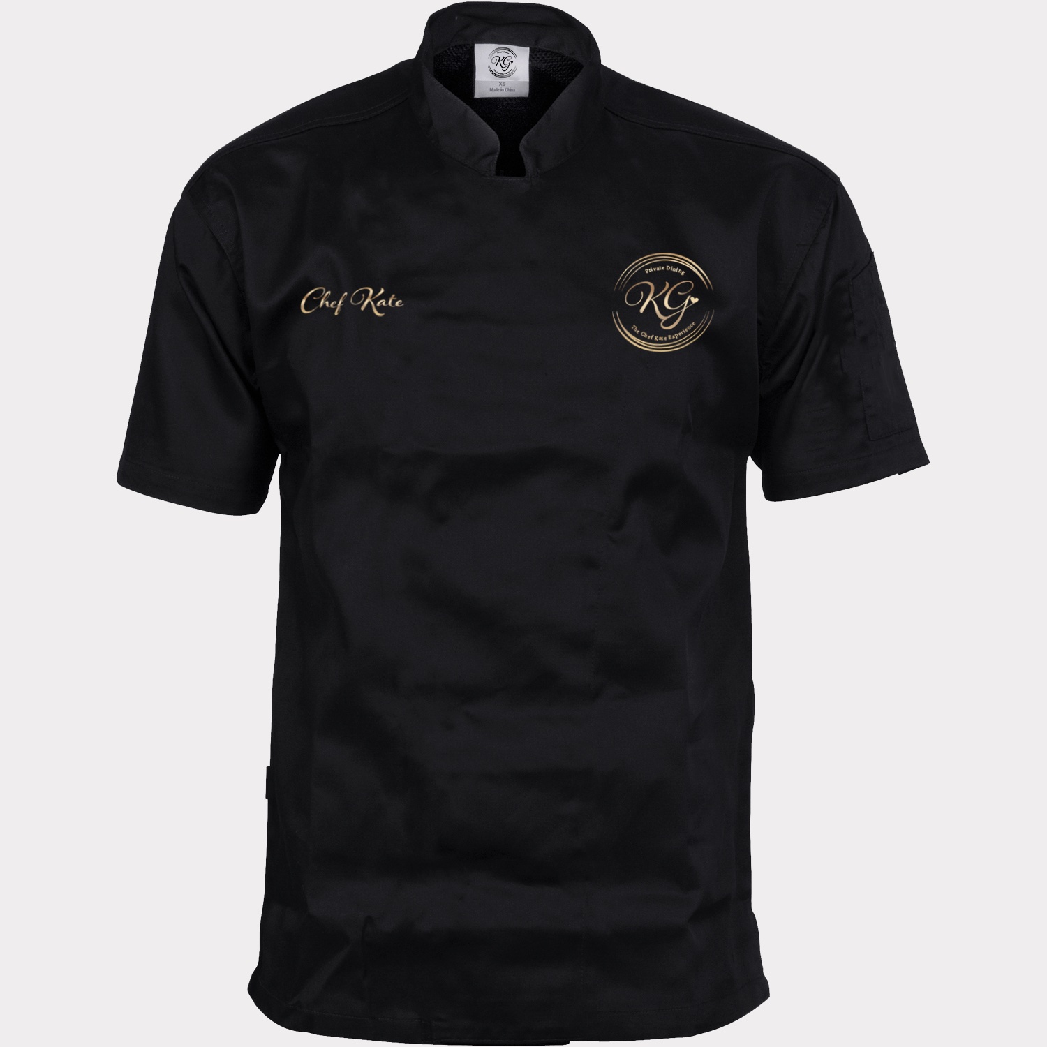 Custom black chef coat with 'Chef Kate' embroidered in gold script and a gold 'KG — Private Dining' monogram emblem